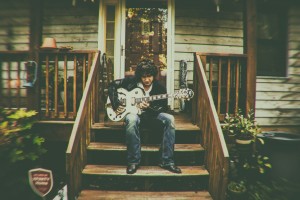 Gooding playing guitar on the porch